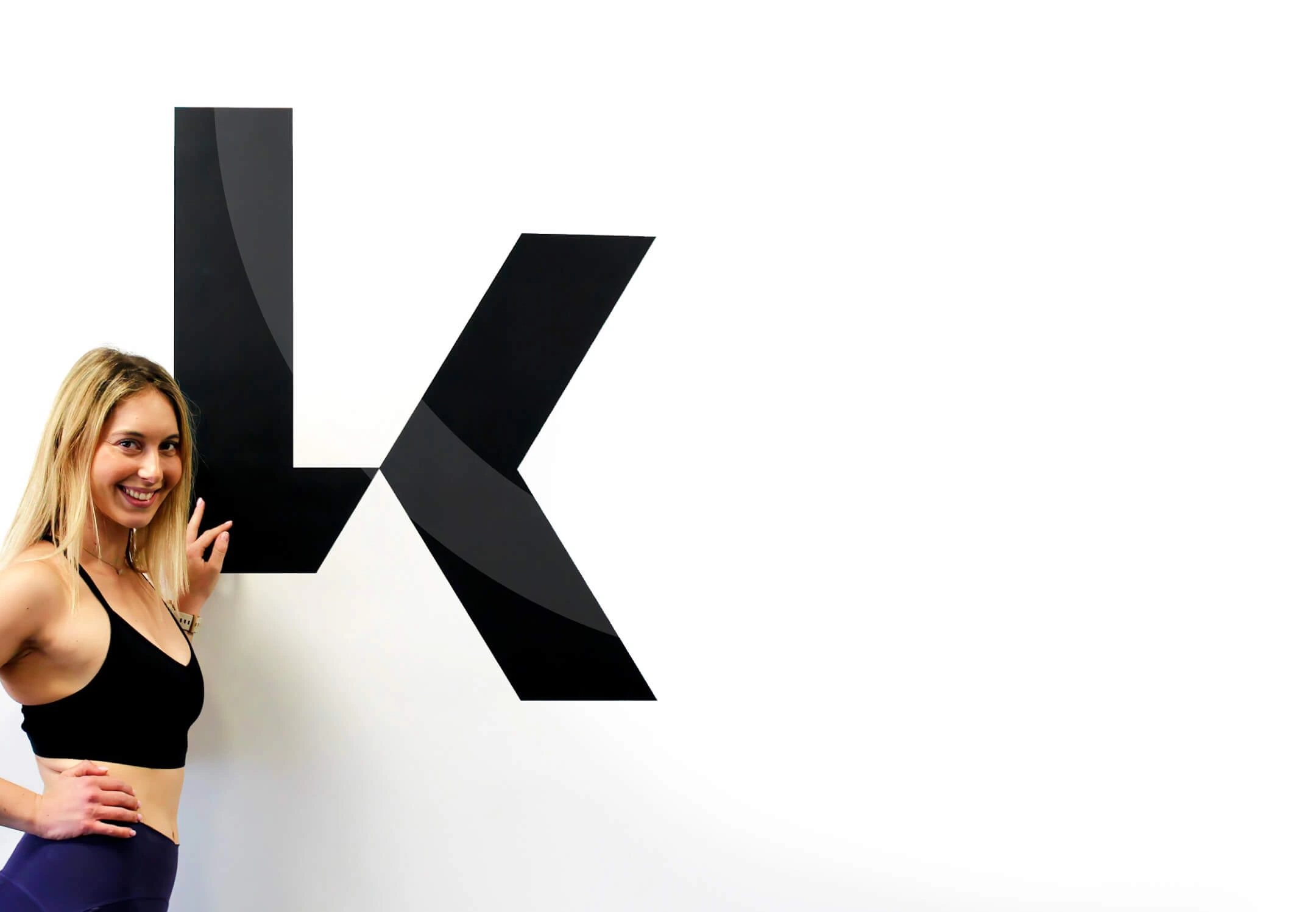 לירון קרני מצטלמת בסטודיו LK על רקע לוגו הסטודיו